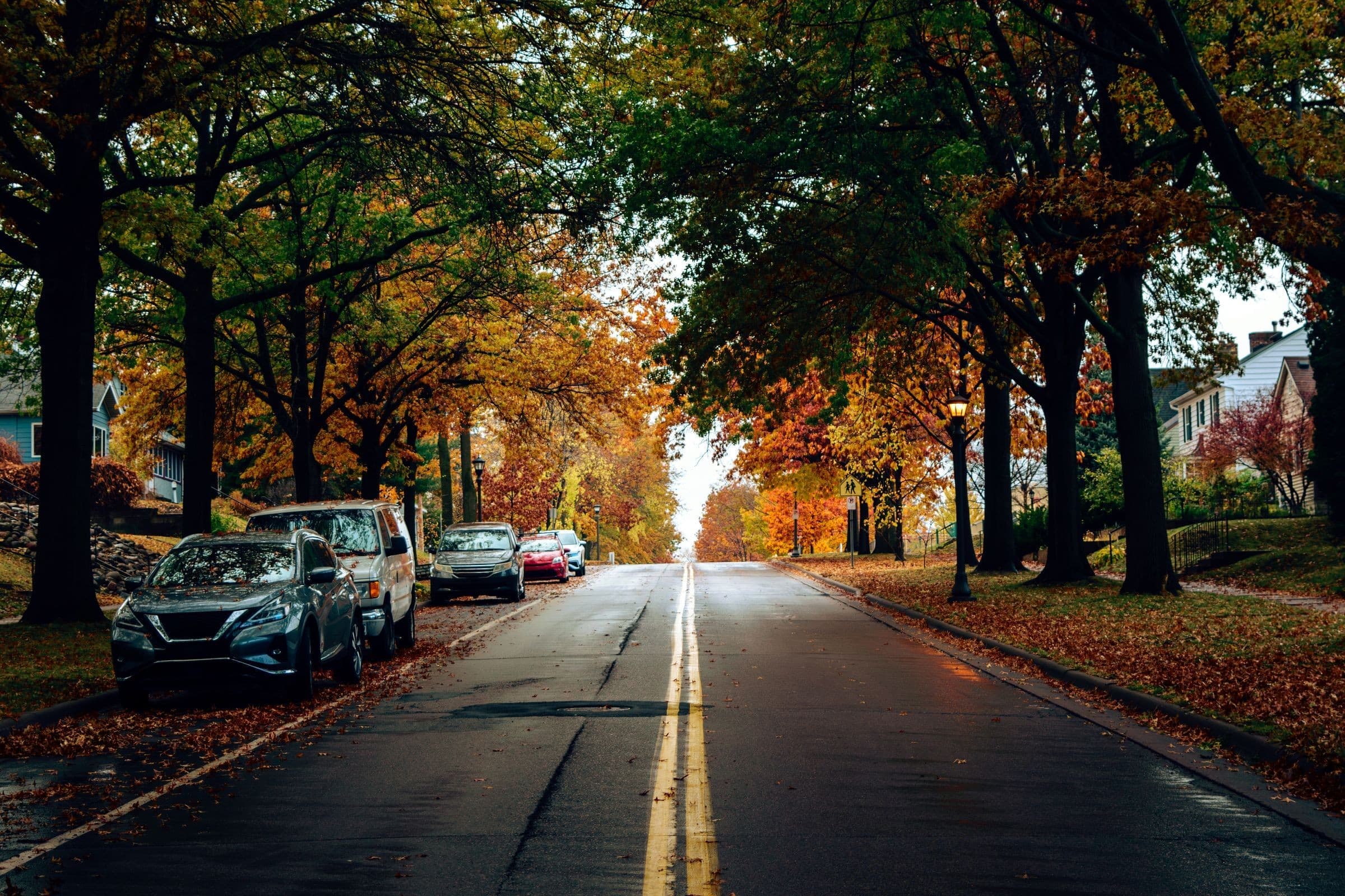 Towing Washington IL: tree-lined residential street in autumn with parked cars, the kind of road our trucks cover around Washington